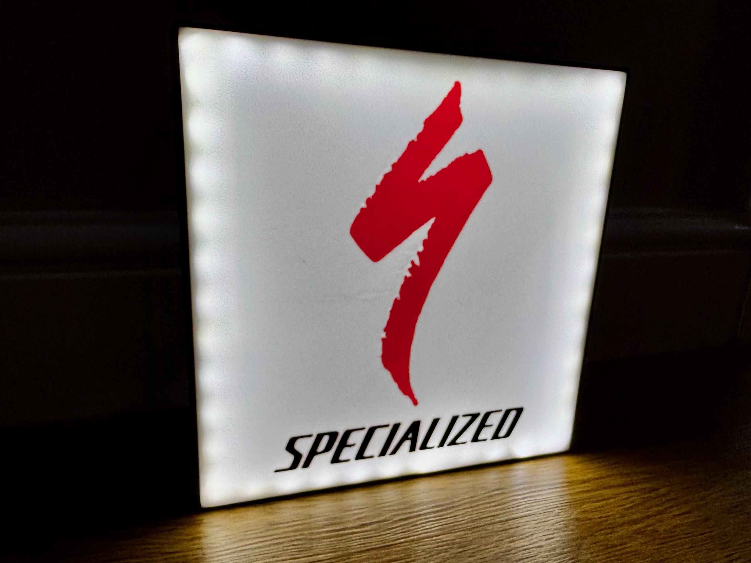 Illuminated Specialized light box with red S logo glowing on white background
