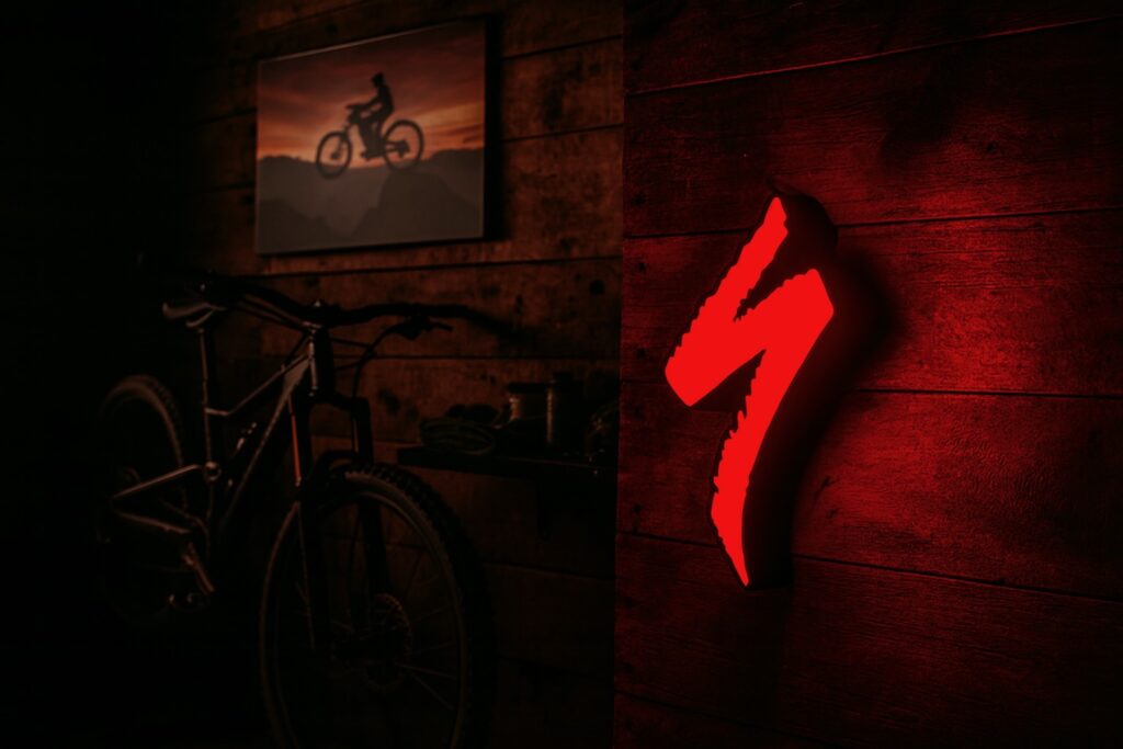 Glowing red Specialized S logo light on wooden surface with dark background